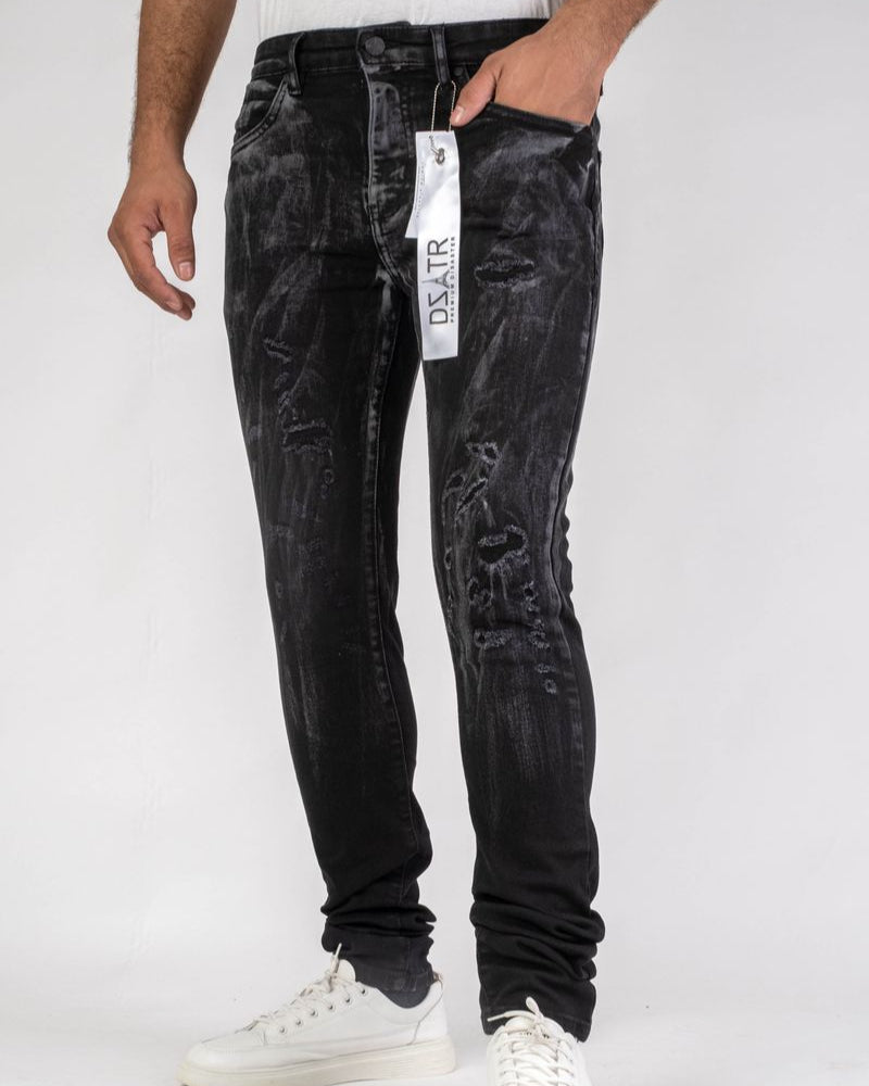 Person wearing black distressed jeans with a visible brand tag on a white background