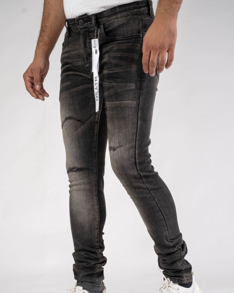 Person wearing black distressed jeans with a white brand label on a white background