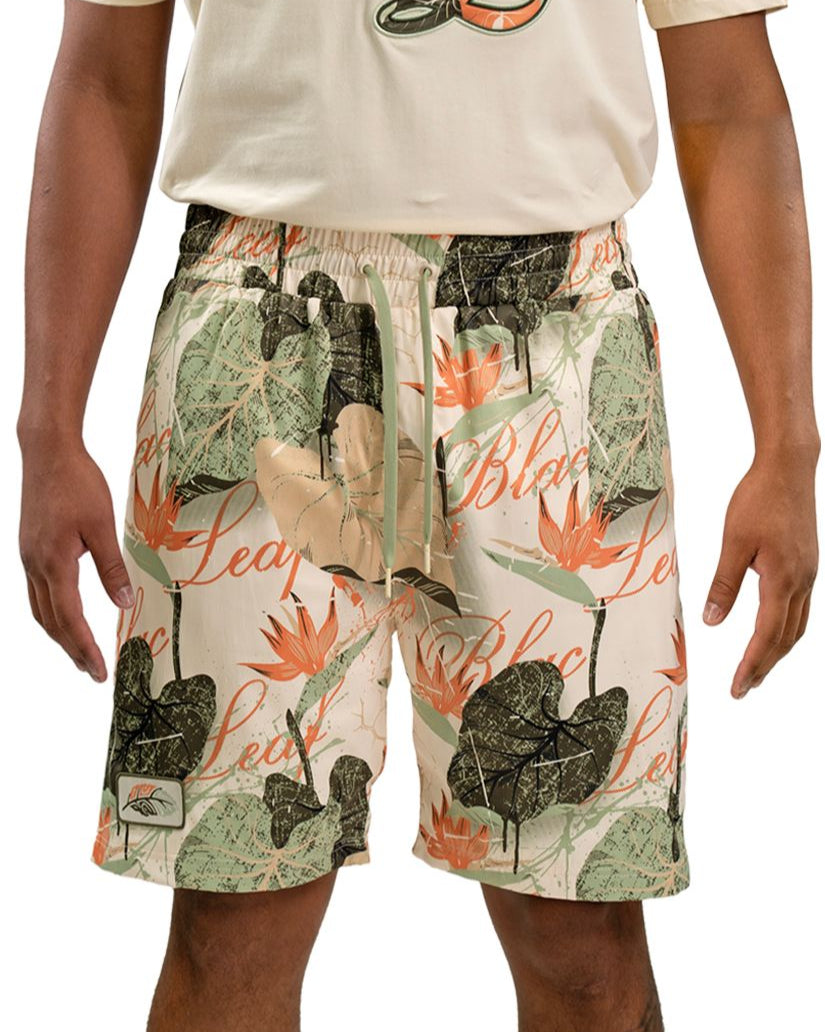 Person wearing a pair of shorts by Blac leaf with a floral and leaf pattern on a plain cream background
