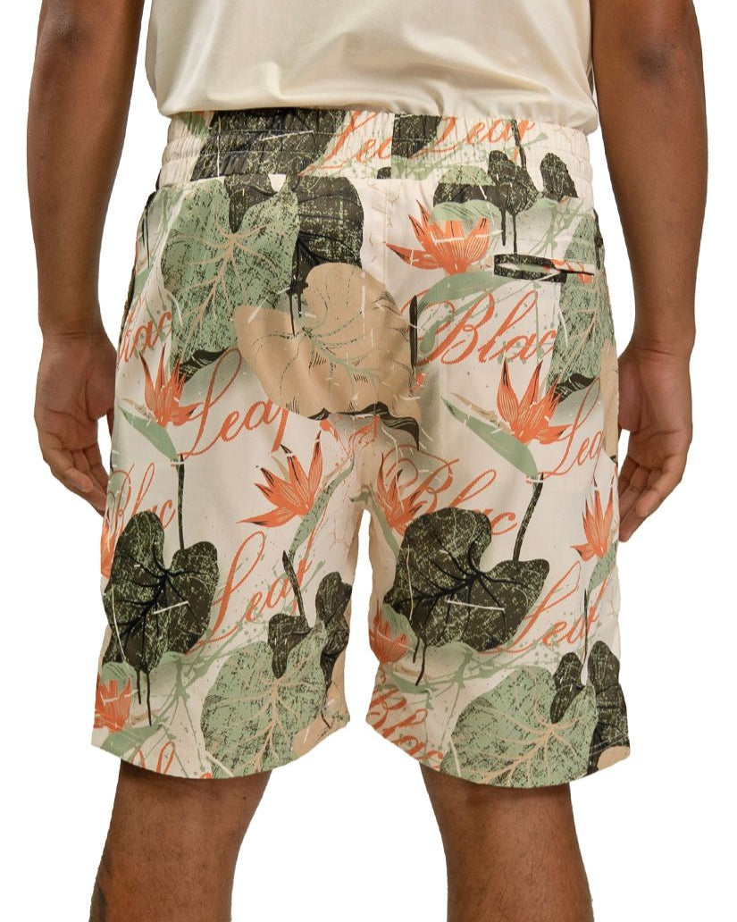 Person wearing a pair of shorts by Blac leaf with a floral and leaf pattern on a plain cream background