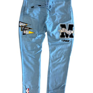Light blue sweatpants with patches and logos on a white background
