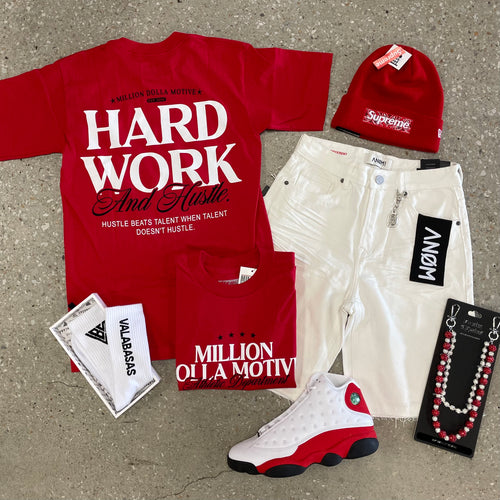 Red and white clothing and accessories including t-shirts, a beanie, and sneakers on a concrete surface.