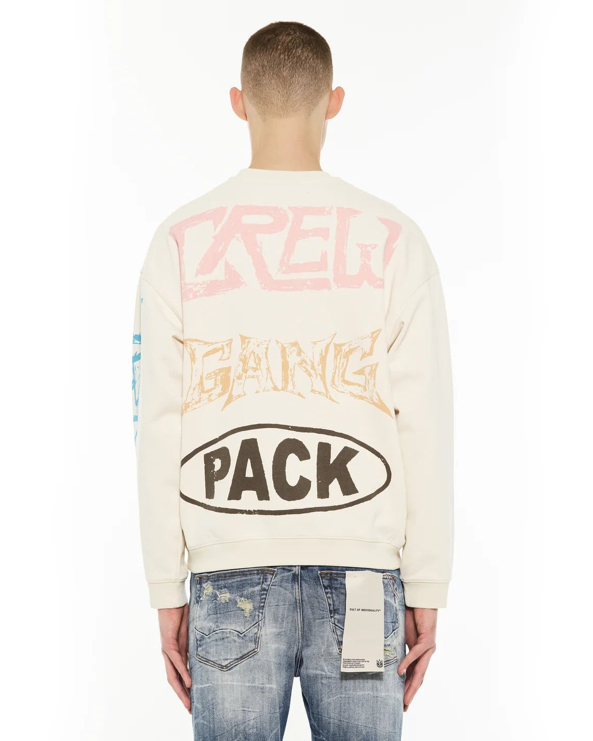 Person wearing a cream sweatshirt with colorful text on the back, standing against a white background