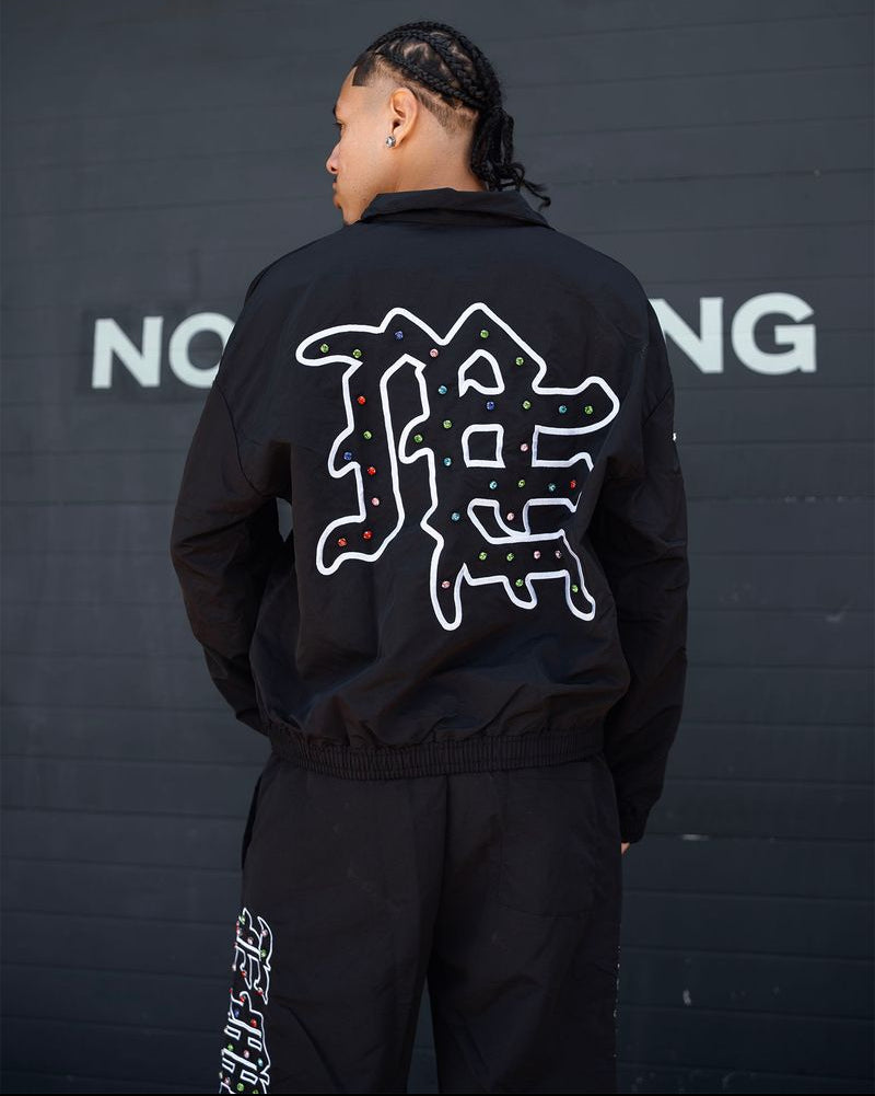 Person wearing a black jacket with white text on the back against a dark background