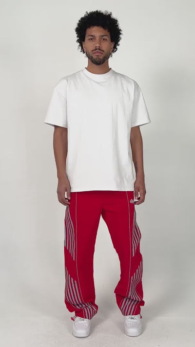 model wearing the red variant of the Roundy pants by brand EPTM. Relaxed posing and energy.
