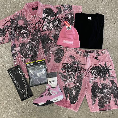 Pink graphic shirt, pants, and accessories on a concrete surface