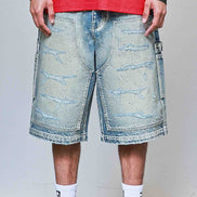 Person wearing light blue denim shorts with a red top and white sneakers on a plain background