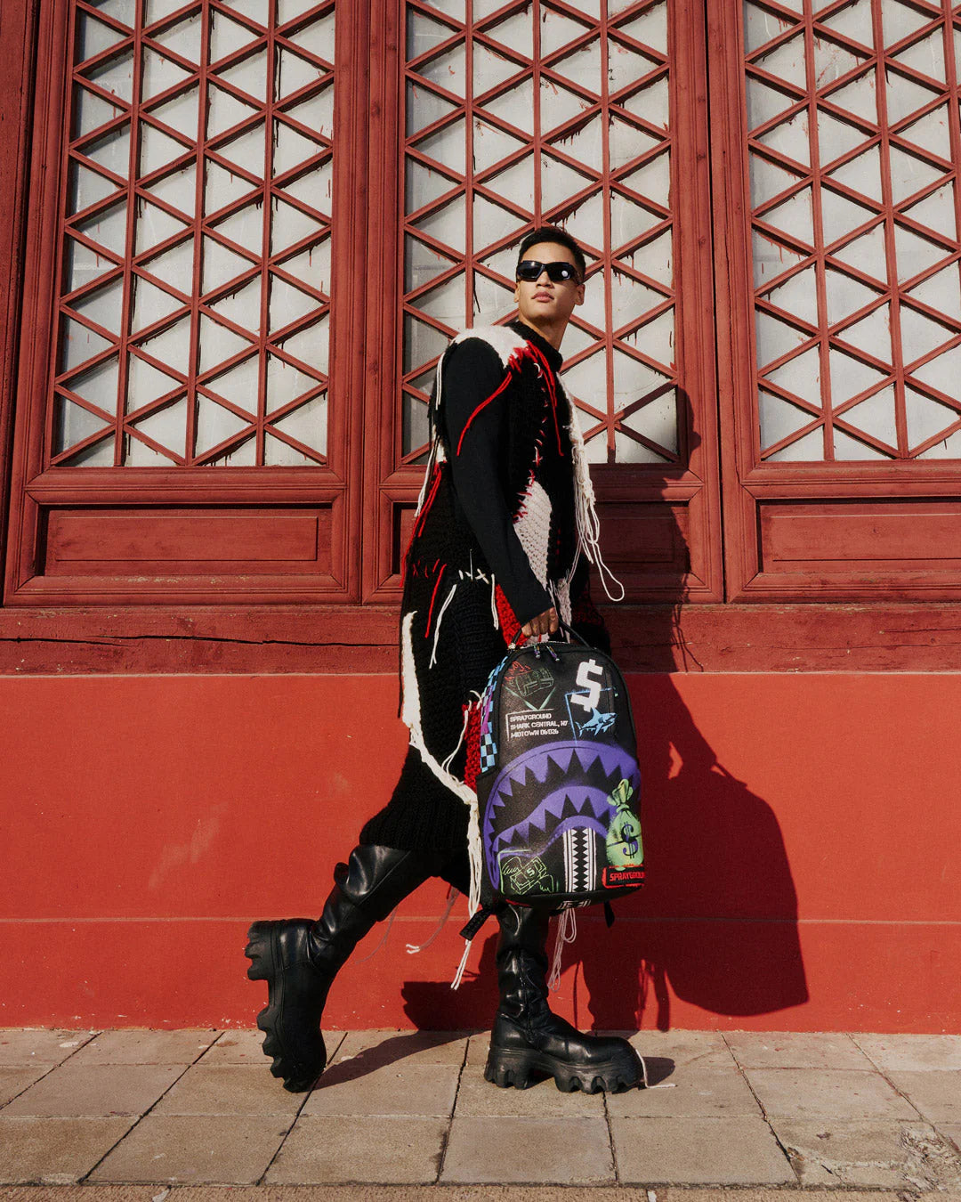 Backpack with colorful graffiti-style graphics and brand logos on a white background by the brand sprayground 