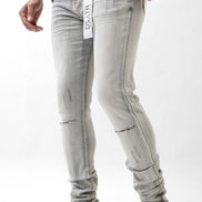 Person wearing light gray jeans with a brand logo on a white background