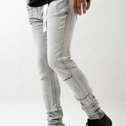 Person wearing light gray distressed jeans and black shoes on a white background
