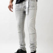 Person wearing light gray distressed jeans with a visible brand tag on a white background
