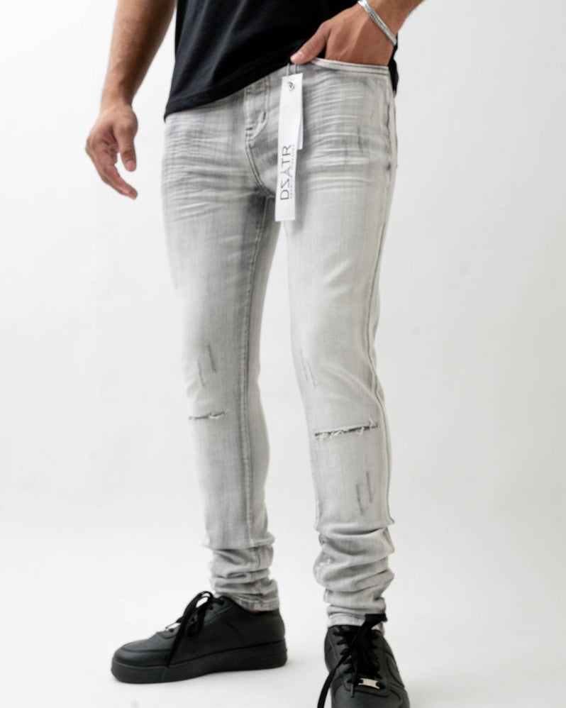 Person wearing light gray distressed jeans with a visible brand tag on a white background