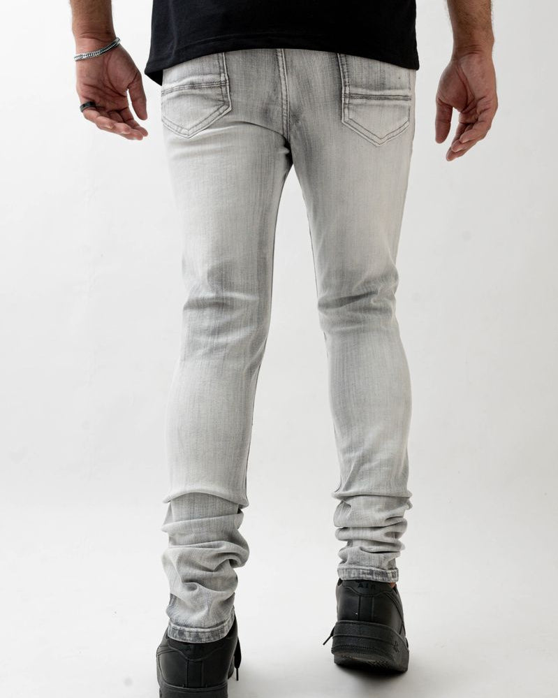 Person wearing light gray jeans and black shoes on a white background