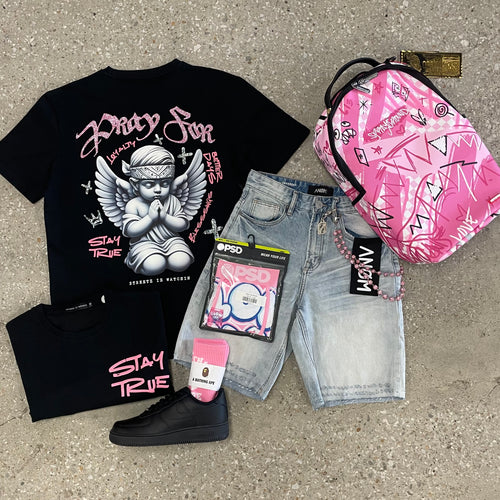 Black t-shirt with angel graphic, pink sneakers, denim shorts, and pink bag on concrete surface