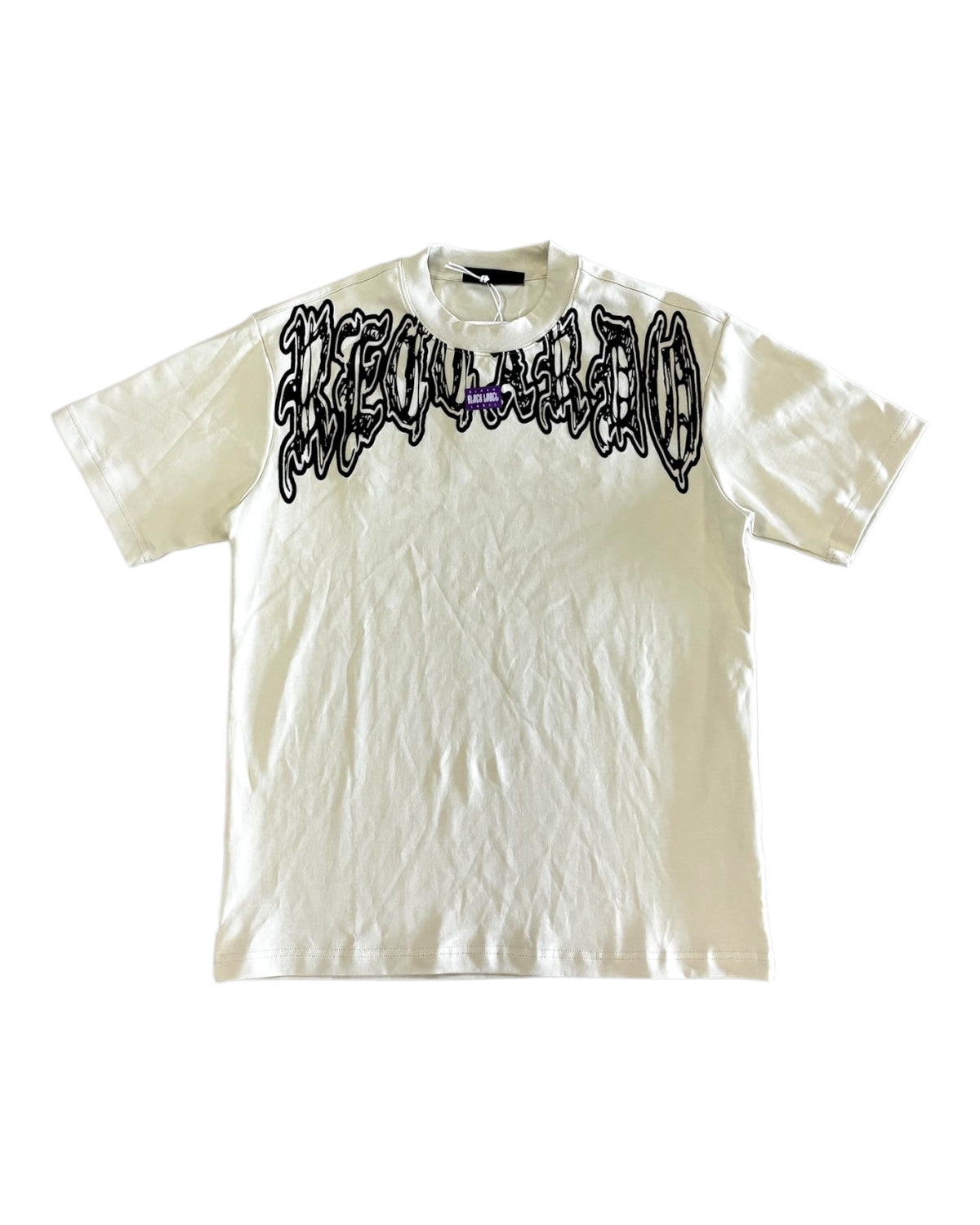 An off-white short-sleeve t-shirt with bold black graphic lettering on the front and back, featuring a gothic flame-style font with accents of purple.