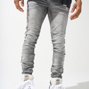 A person wearing light gray distressed skinny jeans and white sneakers.