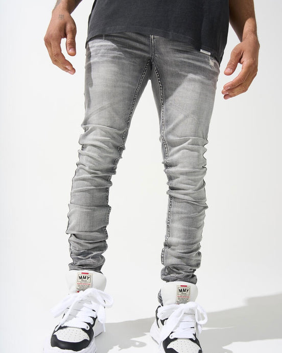 A person wearing light gray distressed skinny jeans and white sneakers.