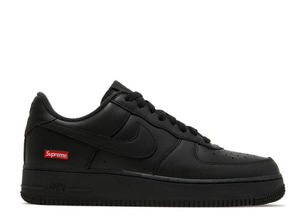 A pair of black Nike Air Force 1 Low sneakers with Supreme branding on the laces and heel tab.
